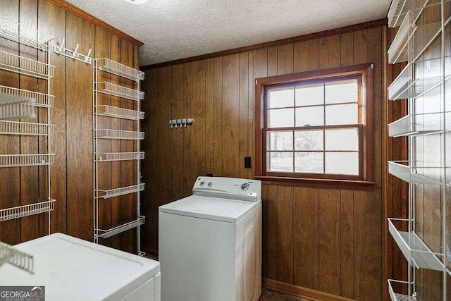 washroom with washer / clothes dryer, wooden walls, and a textured ceiling