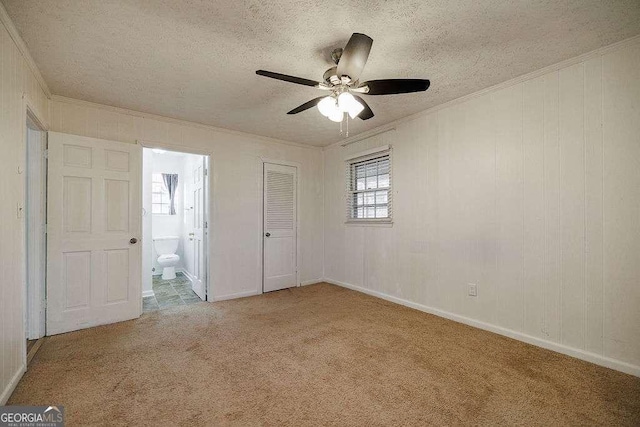 unfurnished bedroom featuring crown molding, ensuite bathroom, carpet, and a textured ceiling