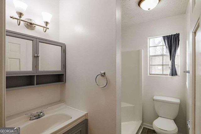 bathroom featuring toilet, vanity, a textured ceiling, and walk in shower