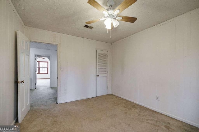 unfurnished bedroom featuring crown molding, ceiling fan, light carpet, and a textured ceiling