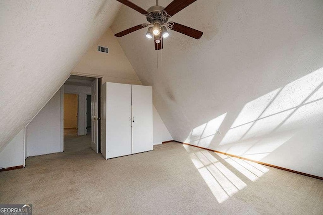 bonus room with lofted ceiling, light colored carpet, and a textured ceiling