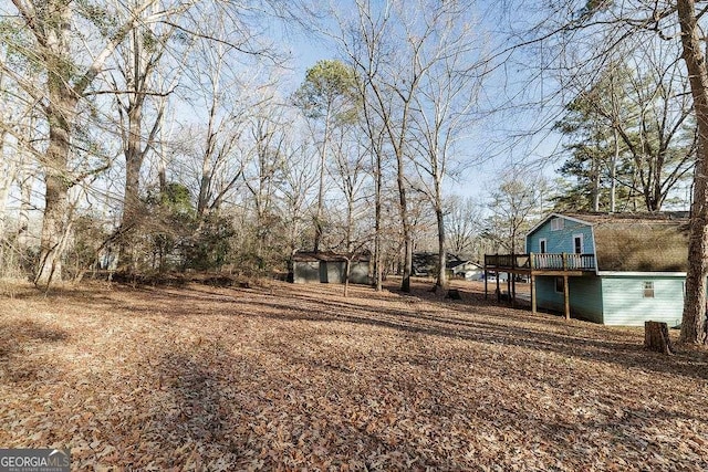 view of yard with a garage, a wooden deck, and an outdoor structure