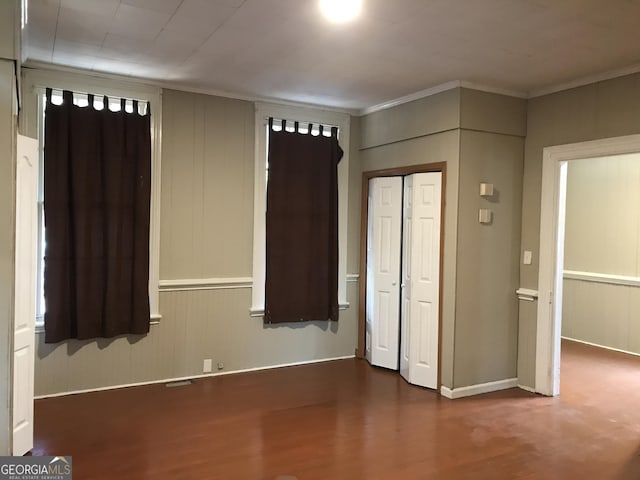 unfurnished bedroom with wood finished floors and crown molding