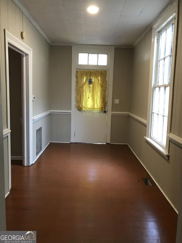 empty room with ornamental molding, wood-type flooring, and a wealth of natural light