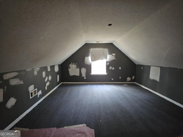 additional living space featuring carpet floors, vaulted ceiling, and a textured ceiling