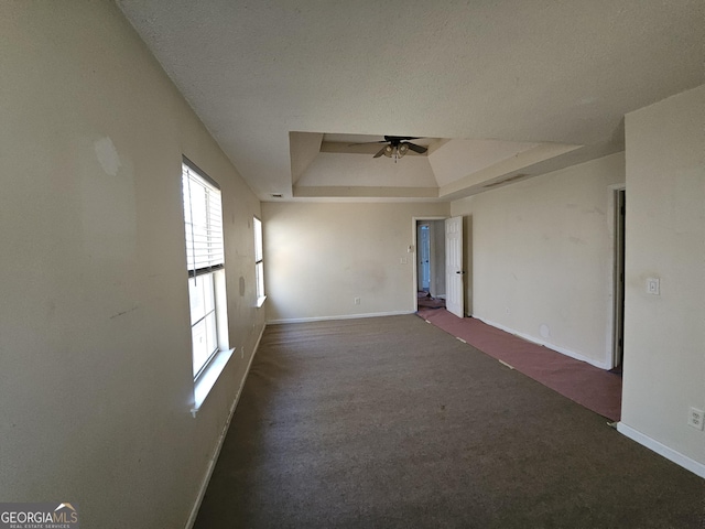 carpeted empty room with ceiling fan and a tray ceiling