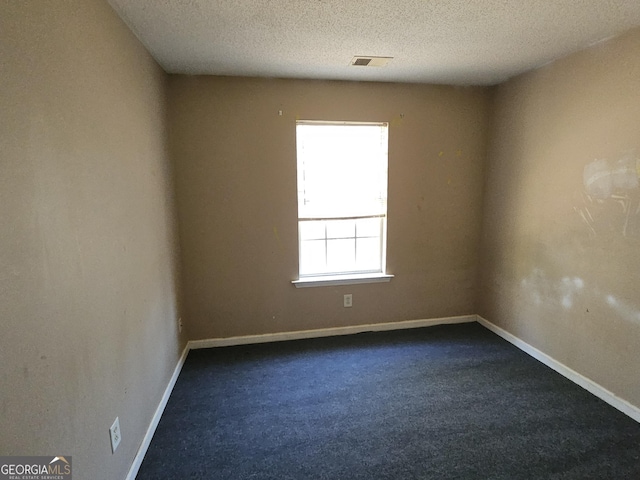 carpeted empty room featuring a textured ceiling