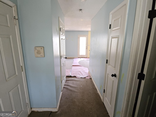 hallway featuring dark colored carpet