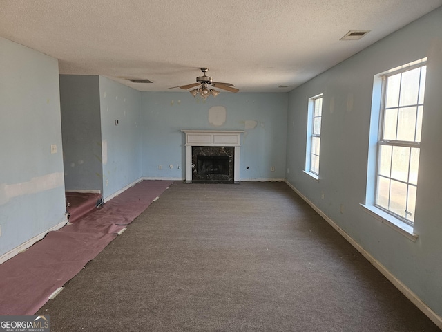 unfurnished living room with ceiling fan, carpet, a textured ceiling, and a high end fireplace