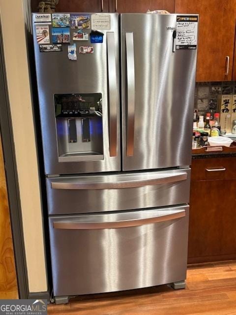 interior details featuring tasteful backsplash, stainless steel refrigerator with ice dispenser, and light wood-type flooring