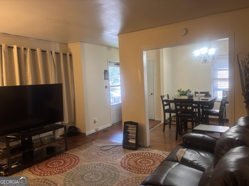 living room with hardwood / wood-style flooring, ornamental molding, and a chandelier