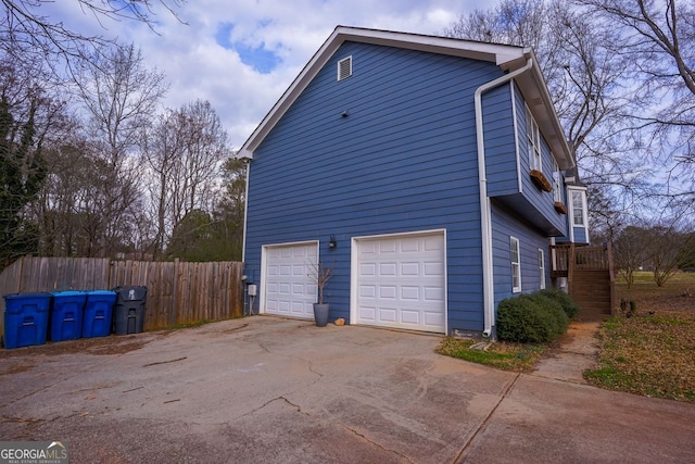 view of side of home featuring a garage, driveway, and fence