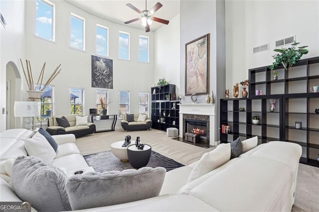 living room with ceiling fan, a high end fireplace, and carpet