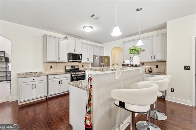 kitchen featuring white cabinetry, hanging light fixtures, stainless steel appliances, and light stone countertops