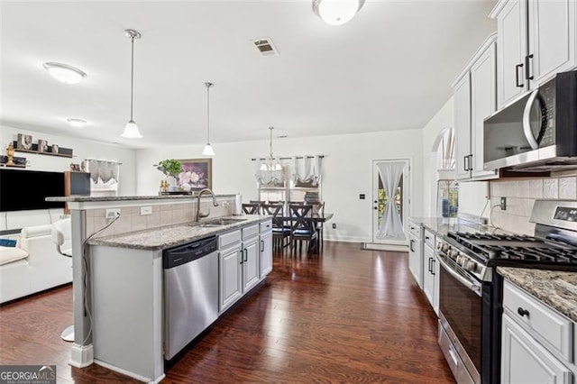 kitchen featuring appliances with stainless steel finishes, sink, white cabinets, and decorative light fixtures