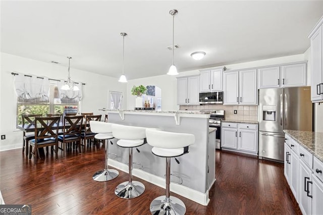 kitchen with hanging light fixtures, a center island with sink, white cabinets, and appliances with stainless steel finishes