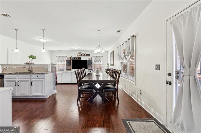 dining area with sink, a notable chandelier, and dark hardwood / wood-style flooring