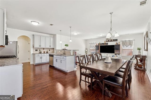 dining area with dark hardwood / wood-style flooring, sink, and a notable chandelier