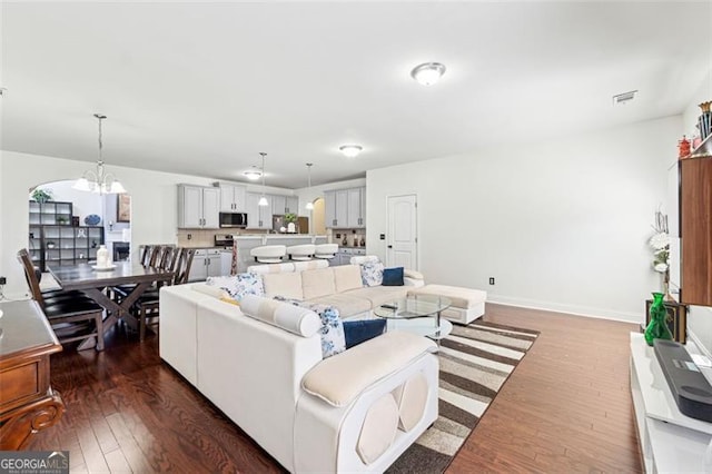 living room with dark wood-type flooring and a chandelier