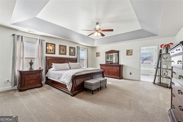 bedroom featuring a tray ceiling, light colored carpet, and ceiling fan