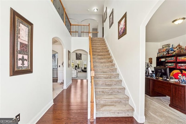 staircase with hardwood / wood-style floors and a high ceiling