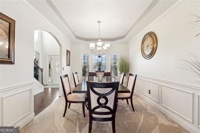 dining area featuring a tray ceiling, ornamental molding, and a chandelier