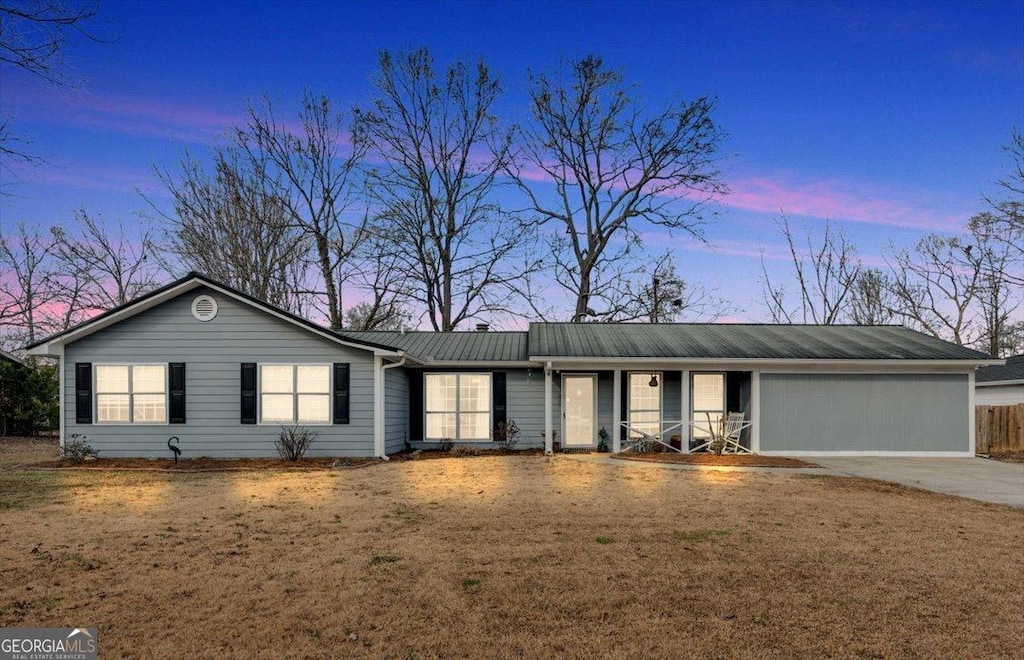 ranch-style home featuring a garage and a yard