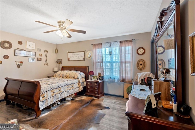 bedroom with ceiling fan, wood-type flooring, and a textured ceiling