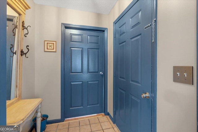 doorway to outside featuring light tile patterned flooring and a textured ceiling