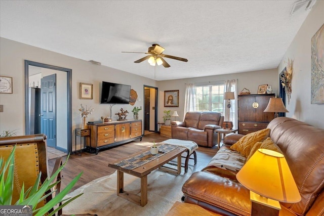 living room featuring hardwood / wood-style floors, a textured ceiling, and ceiling fan