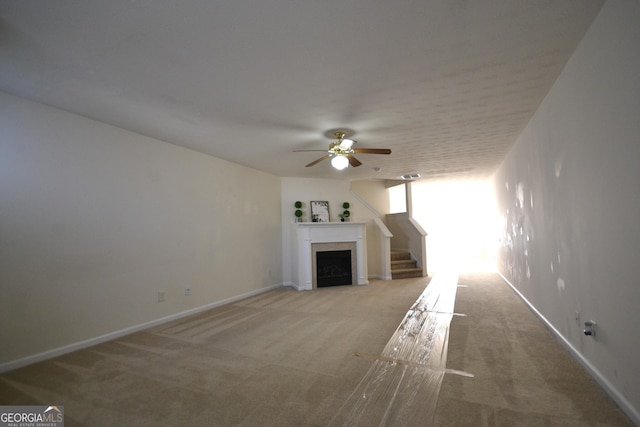 unfurnished living room featuring ceiling fan and light colored carpet