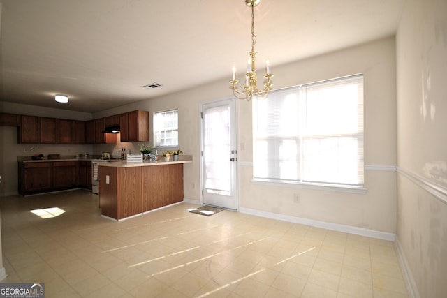 kitchen with a notable chandelier, kitchen peninsula, stainless steel range oven, and decorative light fixtures