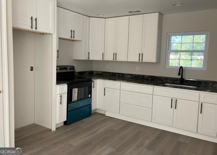 kitchen with dark hardwood / wood-style flooring, sink, white cabinets, and stainless steel electric range oven