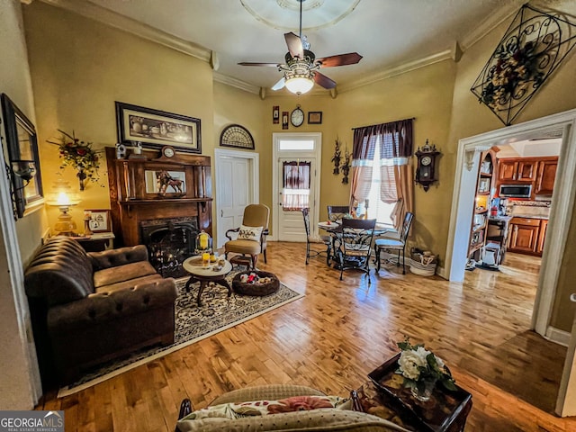 living room with light hardwood / wood-style flooring, ornamental molding, and ceiling fan