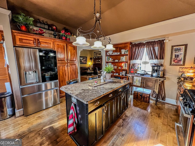 kitchen featuring lofted ceiling, appliances with stainless steel finishes, decorative light fixtures, dark stone counters, and light wood-type flooring