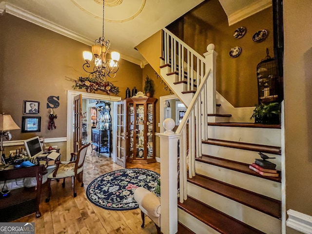 entryway featuring hardwood / wood-style flooring, crown molding, an inviting chandelier, and french doors