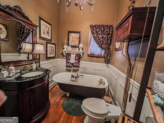 bathroom featuring hardwood / wood-style flooring, vanity, toilet, and a washtub