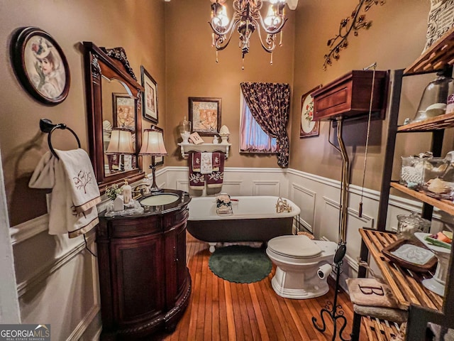 bathroom featuring toilet, a tub, vanity, a notable chandelier, and hardwood / wood-style floors