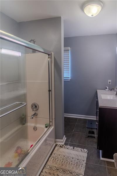 bathroom featuring enclosed tub / shower combo, tile patterned floors, and vanity