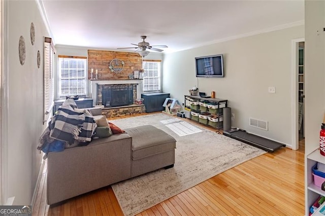 living room featuring a fireplace, crown molding, wood-type flooring, and ceiling fan