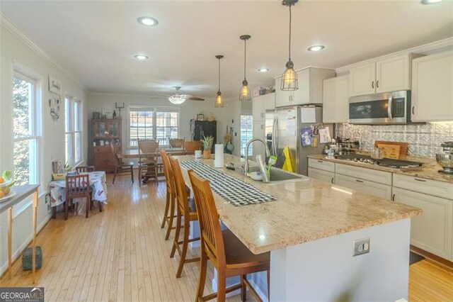 kitchen with appliances with stainless steel finishes, sink, a center island with sink, and white cabinets