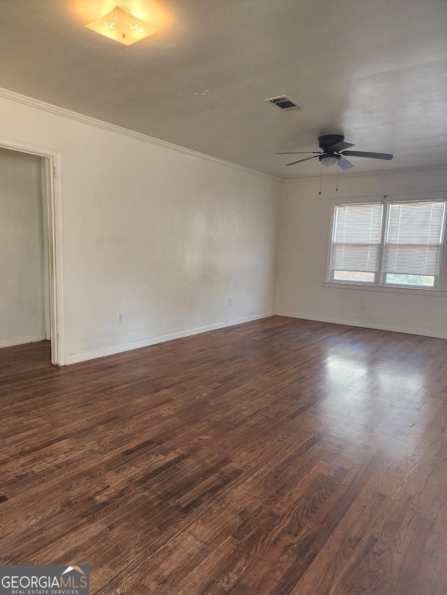 empty room with ornamental molding, dark hardwood / wood-style floors, and ceiling fan