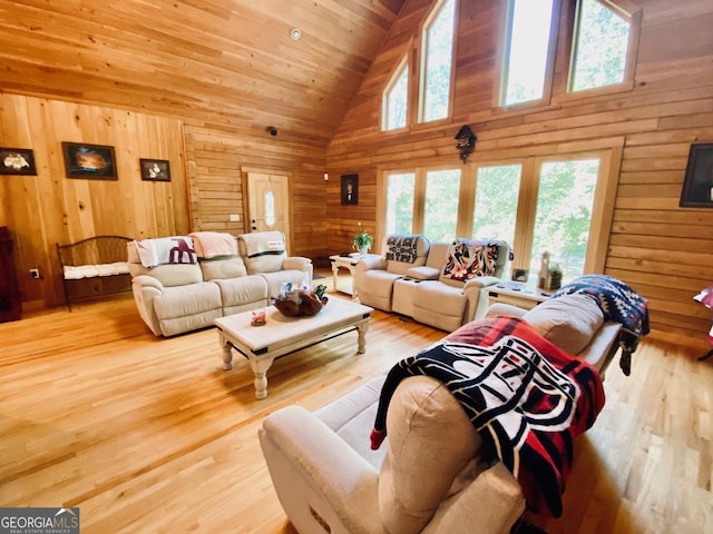 living room featuring light hardwood / wood-style flooring, wooden walls, and a healthy amount of sunlight