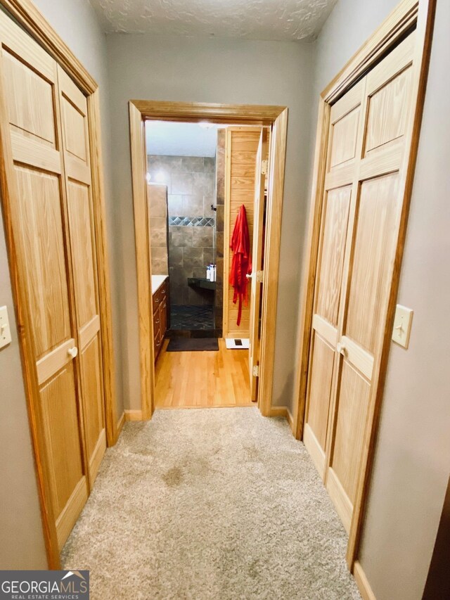 hall with light colored carpet and a textured ceiling