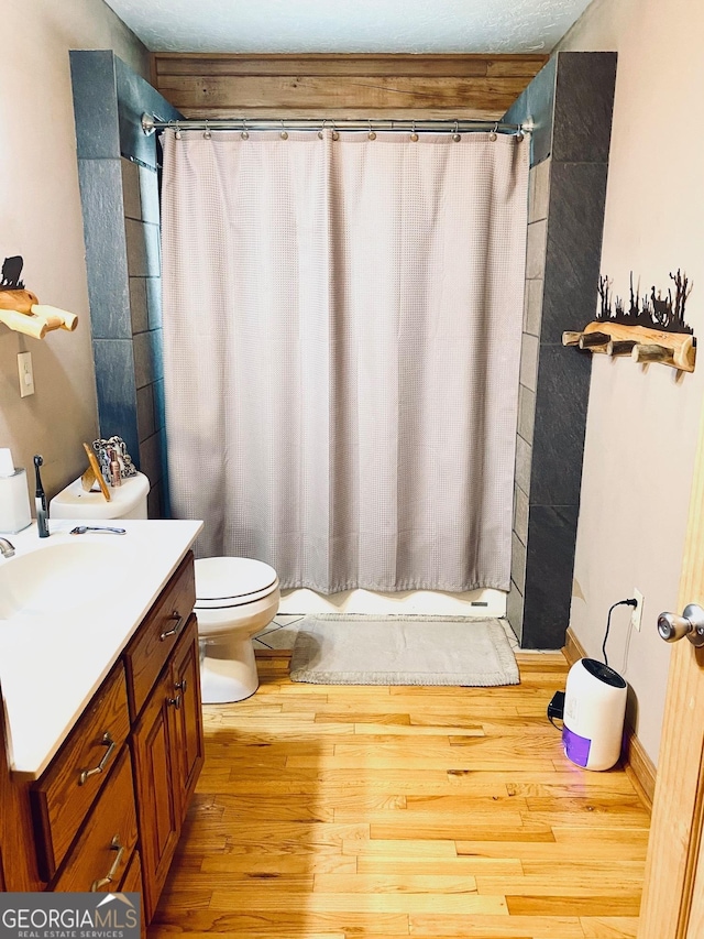 bathroom featuring walk in shower, vanity, toilet, and hardwood / wood-style floors