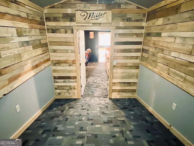 hallway with lofted ceiling and wooden walls