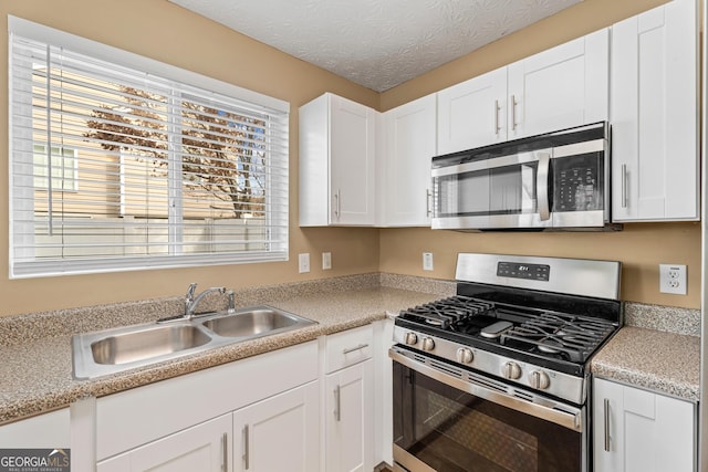 kitchen with stainless steel appliances, white cabinetry, sink, and a textured ceiling