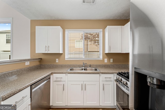 kitchen with plenty of natural light, appliances with stainless steel finishes, sink, and white cabinets