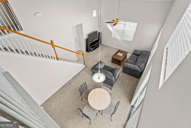 living room featuring ceiling fan, a high ceiling, and carpet