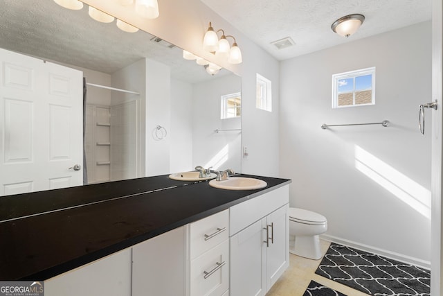 bathroom featuring a shower, vanity, a textured ceiling, and toilet